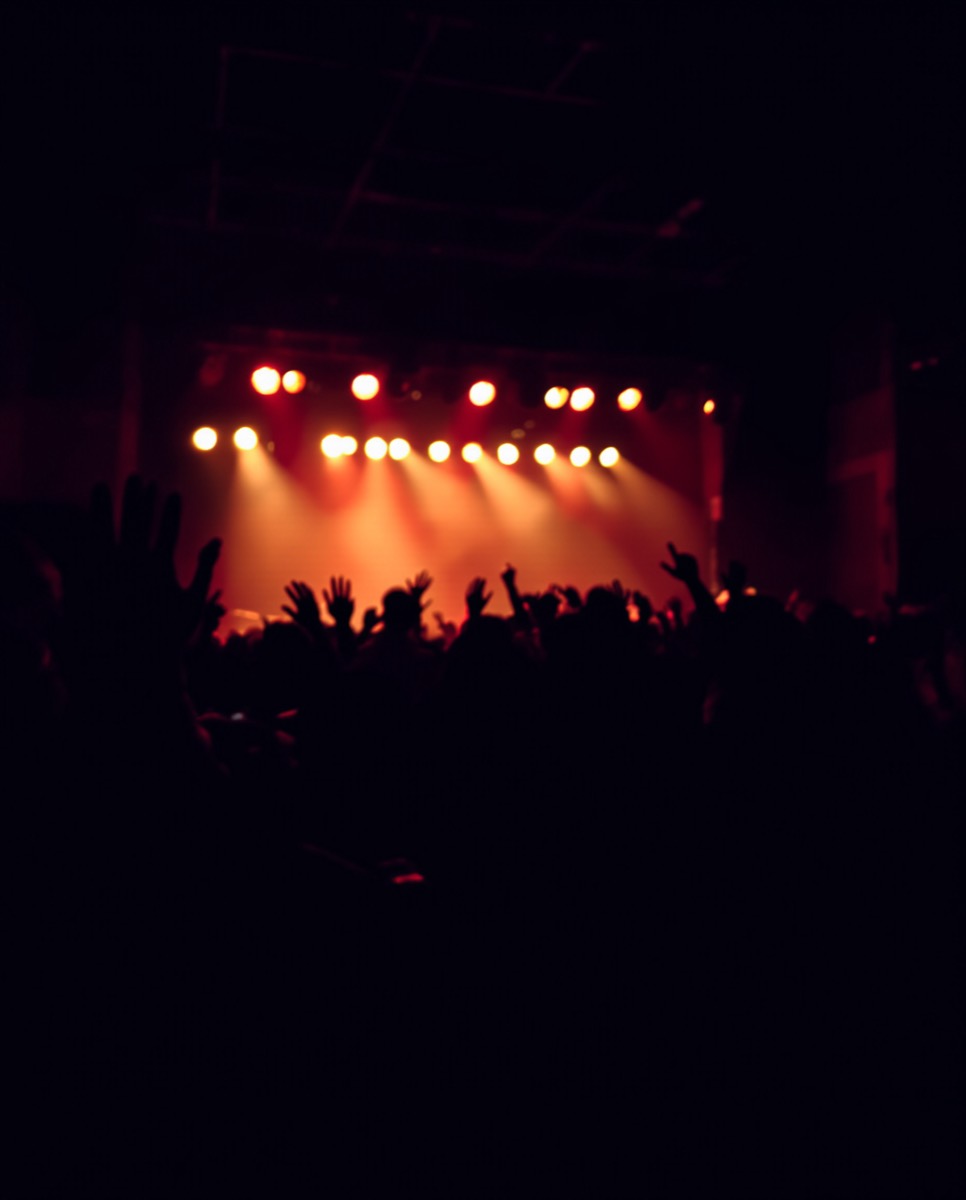 Warm stage lights over a crowd at a small concert.